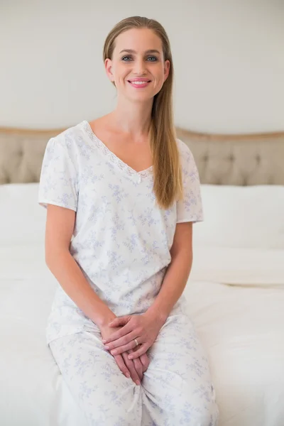 Naturliga leende kvinna som sitter på sängen — Stockfoto