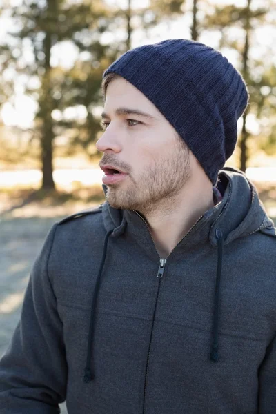 Man in warm clothing looks to his side in forest — Stock Photo, Image