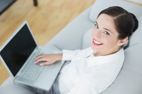 Sorrindo bem vestido jovem mulher usando laptop no sofá — Fotografia de Stock