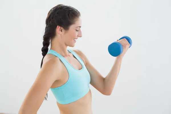 Side view of a smiling woman with dumbbell — Stock Photo, Image