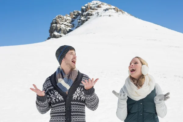 Pareja con las manos abiertas de pie frente a la colina nevada —  Fotos de Stock