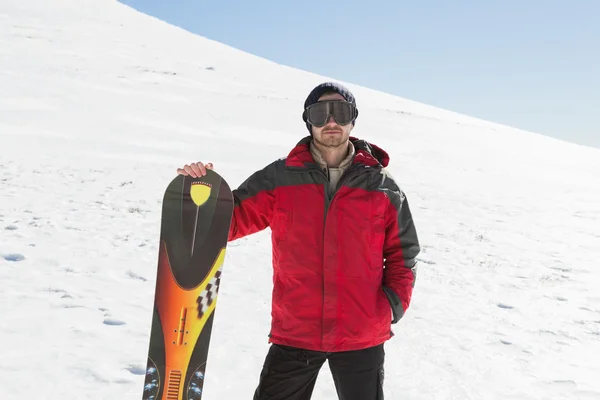 Porträt eines ernstzunehmenden Mannes mit Skibrett im Schnee — Stockfoto