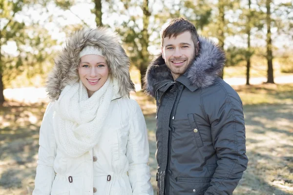 Sonriente pareja en chaquetas de piel campana en el bosque —  Fotos de Stock