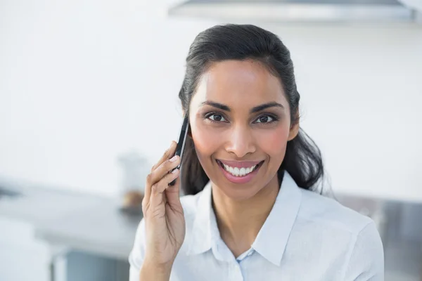 Hübsche junge Frau telefoniert mit ihrem Smartphone in heller Küche — Stockfoto