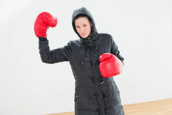 Tought woman in hooded jacket and red boxing gloves — Stock Photo, Image