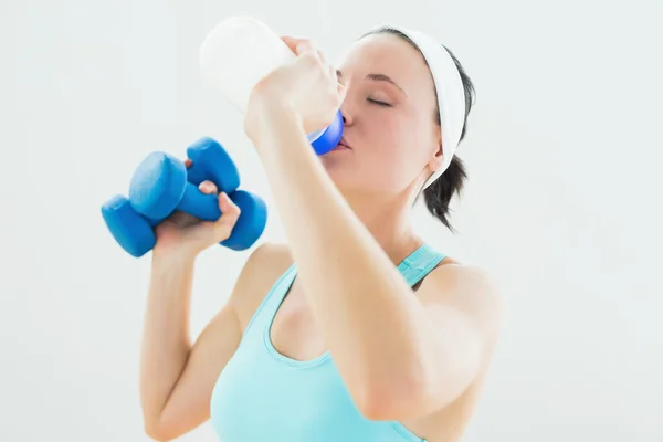 Toned woman with dumbbells drinking water — ストック写真
