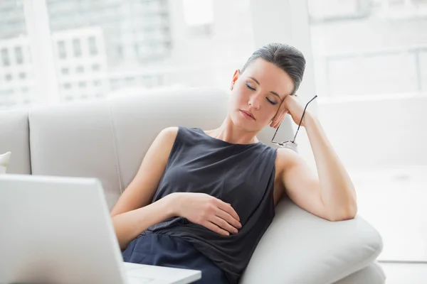 Bela mulher bem vestida descansando no sofá enquanto usando laptop — Fotografia de Stock