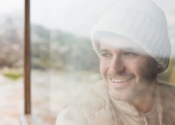 Thoughtful smiling man looking out through window — Stock Photo, Image