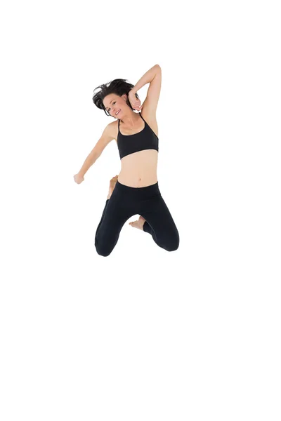 Спортивная молодая женщина прыгает через белый фон — стоковое фото