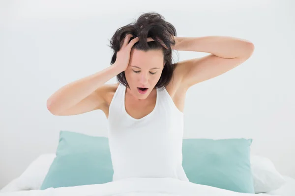 Mujer soñolienta bostezando mientras estira los brazos en la cama — Foto de Stock