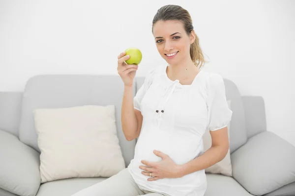 Hermosa mujer embarazada sonriente mostrando una manzana verde — Foto de Stock