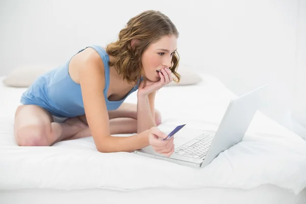 Mujer bonita concentrada usando su cuaderno para ir de compras a casa —  Fotos de Stock