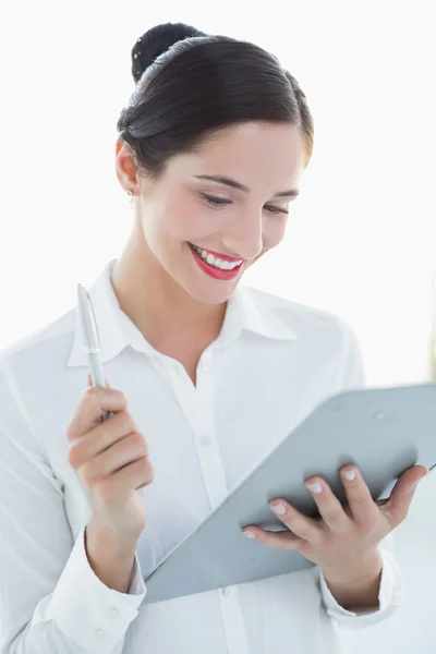 Улыбающаяся деловая женщина с планшетом и ручкой — стоковое фото