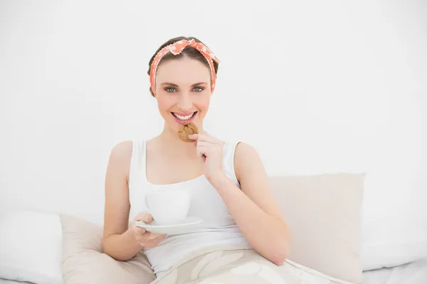 Mulher sorridente comendo um biscoito — Fotografia de Stock