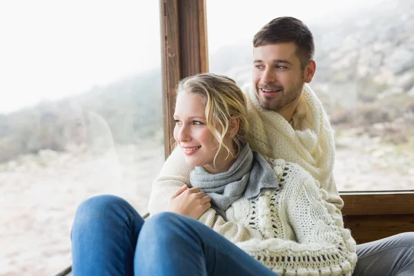 Couple in winter wear looking out through cabin window — Stock Photo, Image