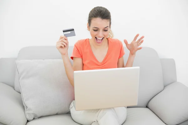 Beautiful happy woman home shopping with her notebook sitting on couch — Stock Photo, Image