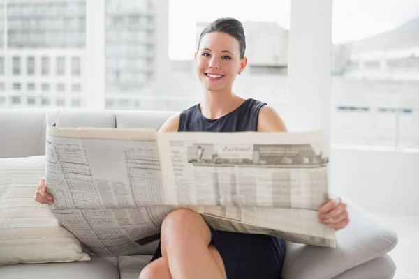 Glimlachende zakenvrouw in prachtige lezing krant op sofa — Stockfoto