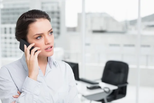 Femme d'affaires élégante sérieuse utilisant un téléphone portable dans le bureau — Photo