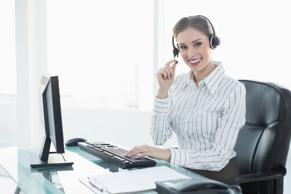 Wunderschöne schicke Agentin mit Headset sitzt an ihrem Schreibtisch — Stockfoto