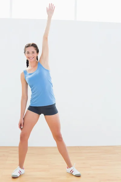 Volledige lengte van een vrouw die zich uitstrekt hand in fitnesscentrum — Stockfoto