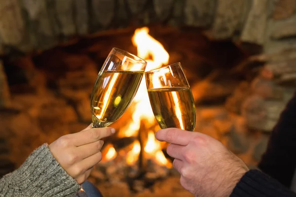 Hands toasting champagne flutes in front of fireplace — Stock Photo, Image