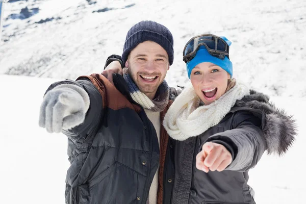 Alegre pareja en chaquetas apuntando a la cámara en la nieve cubierta la —  Fotos de Stock