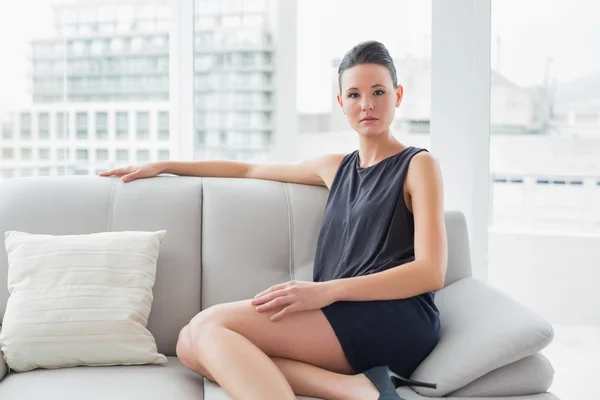 Poważne dobrze ubrana kobieta siedzi na kanapie w domu — Zdjęcie stockowe