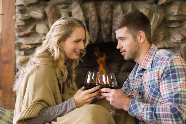 Couple toasting wineglasses in front of lit fireplace — Stock Photo, Image