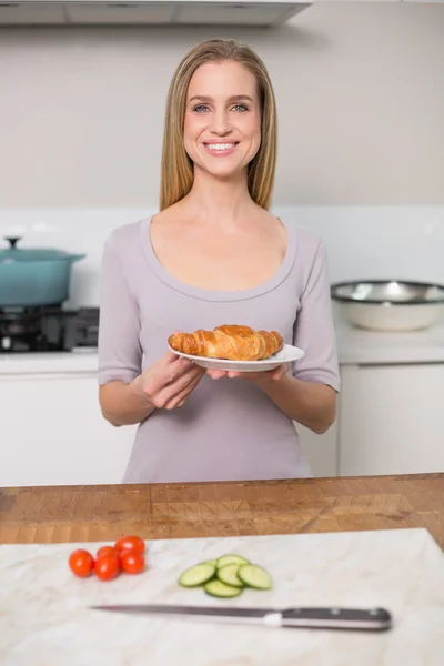 Smiling gorgeous model holding plate with croissant — Stock Photo, Image