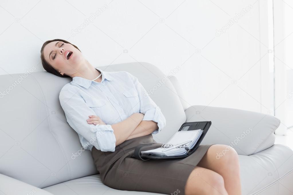 Tired well dressed woman sitting and sleeping on sofa