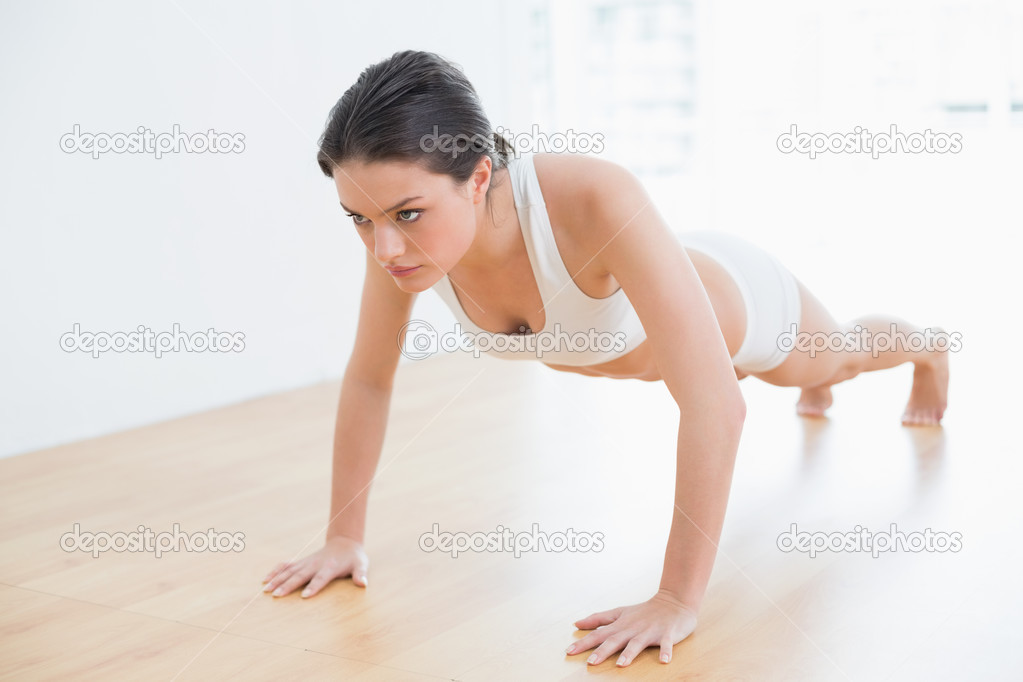 Full length of a sporty young woman doing push ups