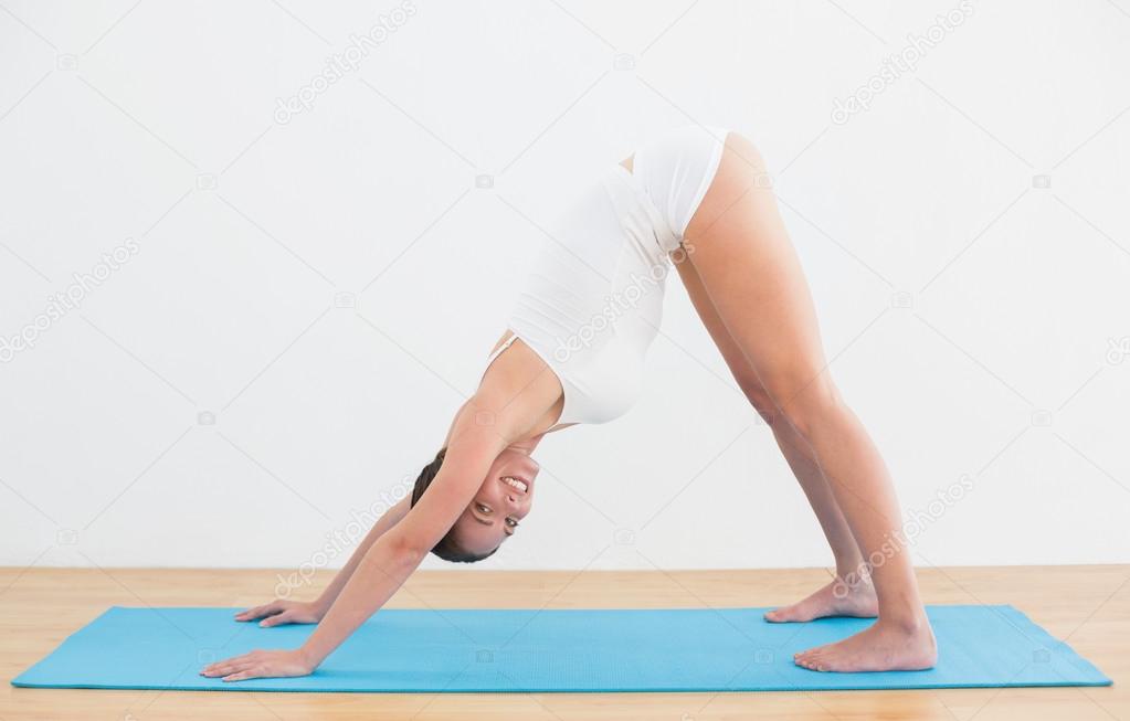 Side view of a smiling woman exercising on mat