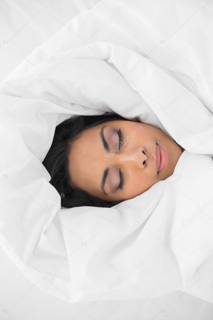 Beautiful woman sleeping lying under cover on her bed