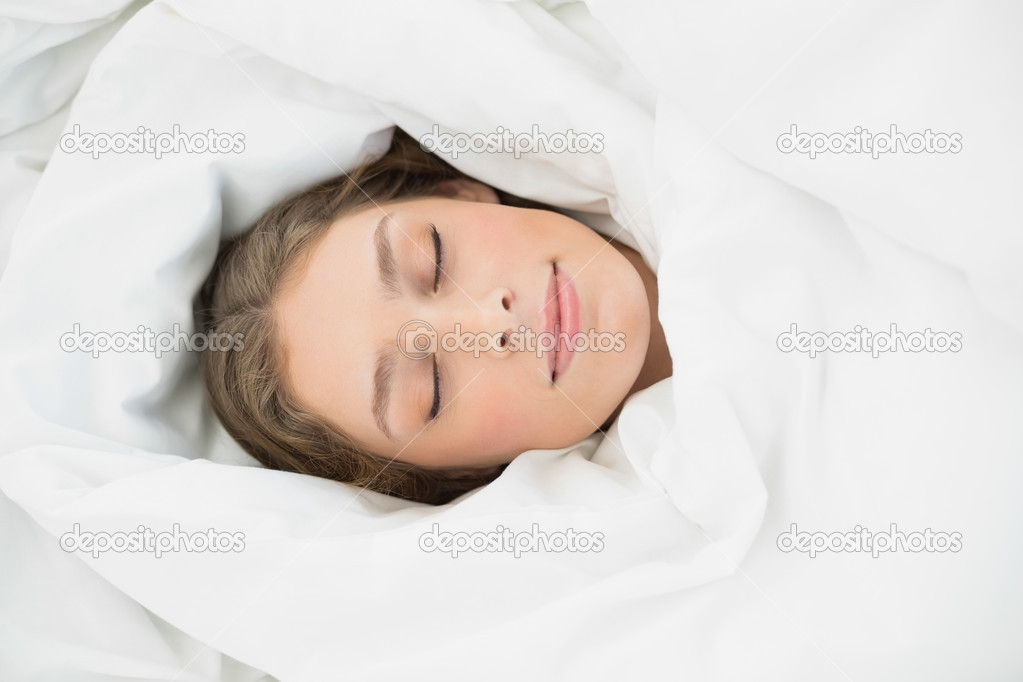 Beautiful woman lying sleeping under the cover on her bed