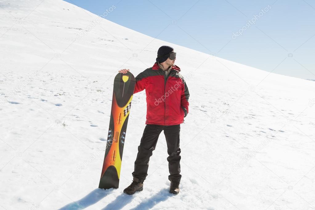 Full length of a man with ski board looking away on snow