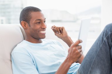 casual gülümseyen afro man dijital tablet kanepe üzerinde kullanma