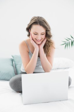 laptop yatakta Casual esmer bakarak gülen