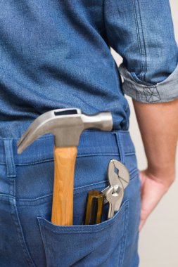 Several tools in a man's rear denim pocket