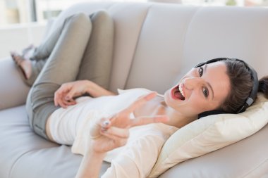 neşeli rahat genç kadın kanepe üzerinde müzik keyfi