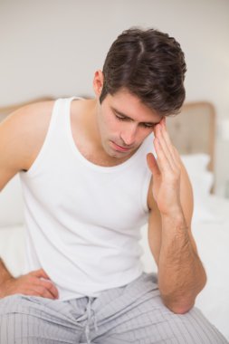yatakta baş ağrısı çeken adam
