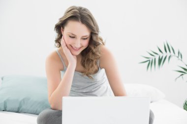 laptop yatakta Casual esmer bakarak gülen