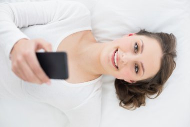 yatakta cep telefonu ile genç esmer