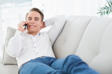 kanepede yatan ise cep telefonu kullanarak rahat genç adam