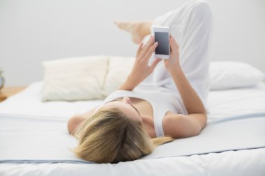 onun smartphone kullanarak onu yatakta yatarken şirin huzurlu kadın