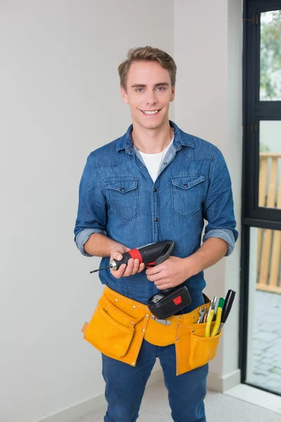 Handyman sosteniendo un taladro con cinturón de herramientas alrededor de la cintura — Foto de Stock