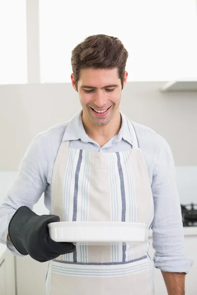 Man smelling food in baking dish in kitchen — Stock fotografie