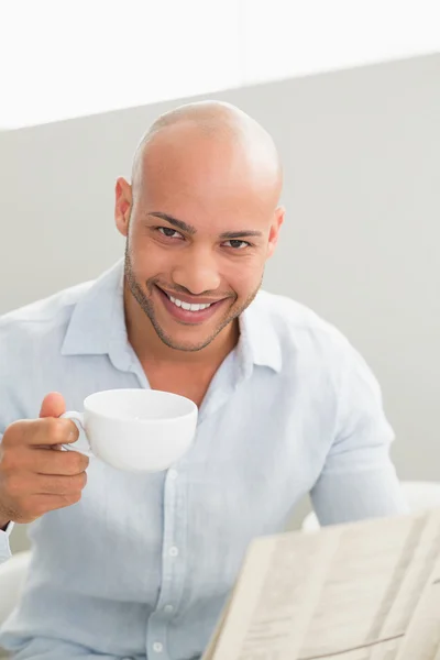 Homme souriant prenant un café tout en lisant le journal — Photo