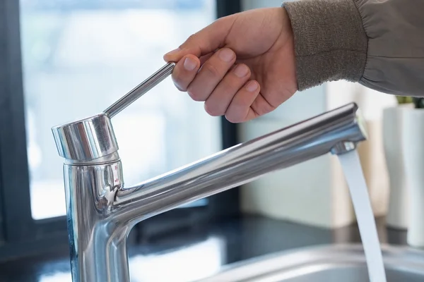 La mano del fontanero abre un grifo de agua en el baño —  Fotos de Stock