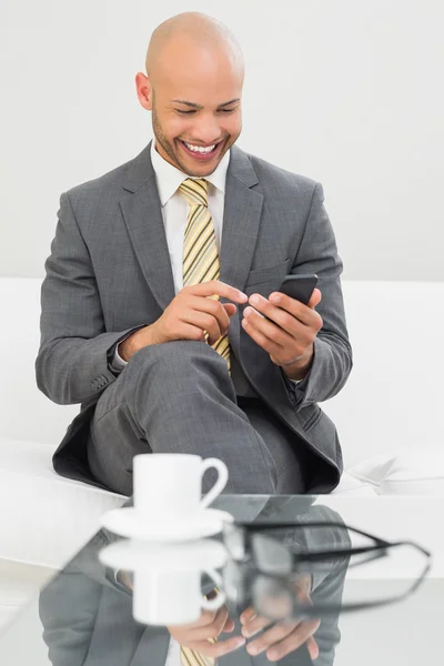 Businessman text messaging on sofa at home — Stock Photo, Image
