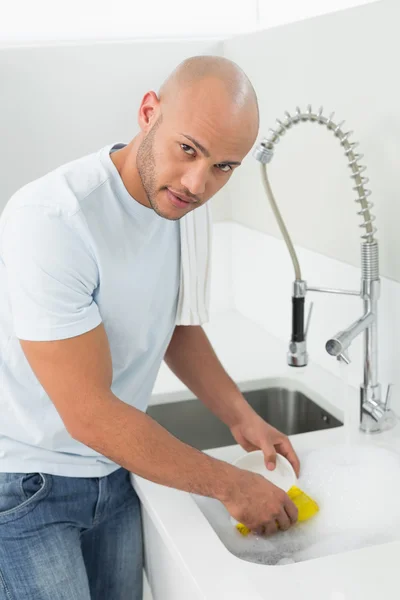 Young man doing the dishes at kitchen sink — Stock Photo, Image